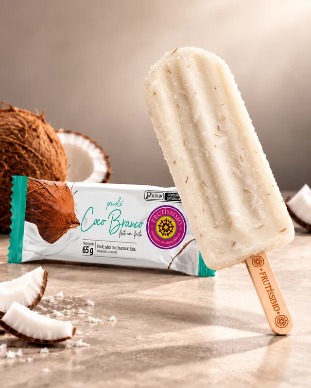 Picolé de coco branco Frutíssimo ao lado da embalagem e de pedaços de coco